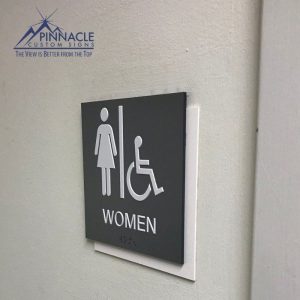 Raised letters, braille, and high contrasting restroom signs are ADA compliant